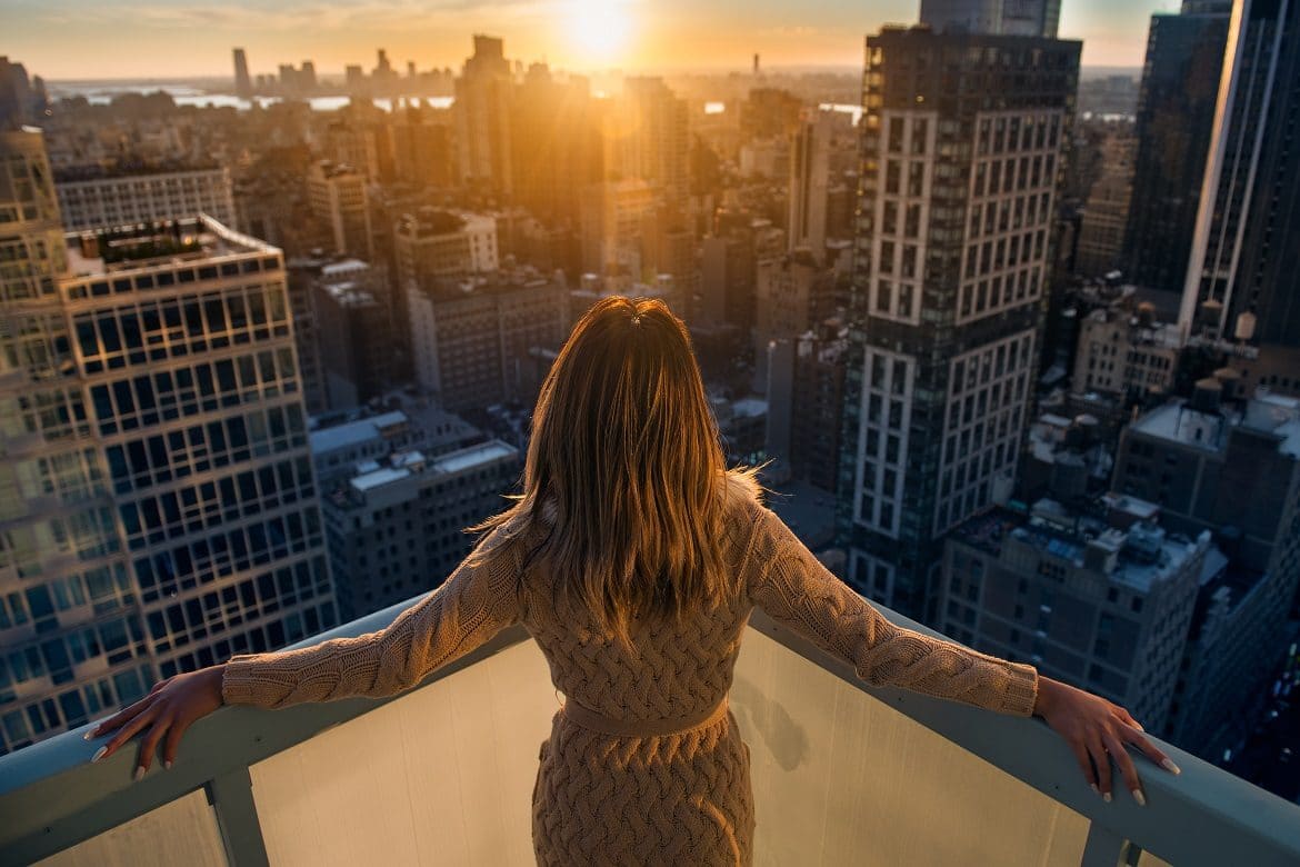 Wealthy woman enjoying the sunset standing on the balcony at luxury apartments in New York City