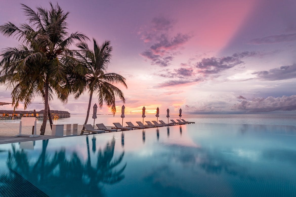 Idyllic sunset beach scene, infinity pool at a Luxury resort
