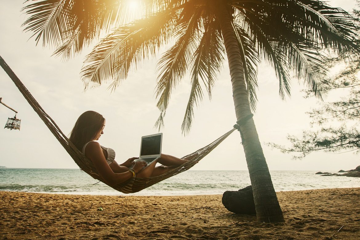 Young woman blogging remotely on her laptop in paradise